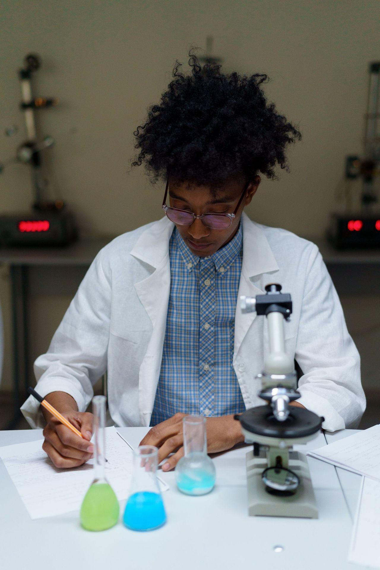 Estudante de bata branca a tomar notas num laboratório